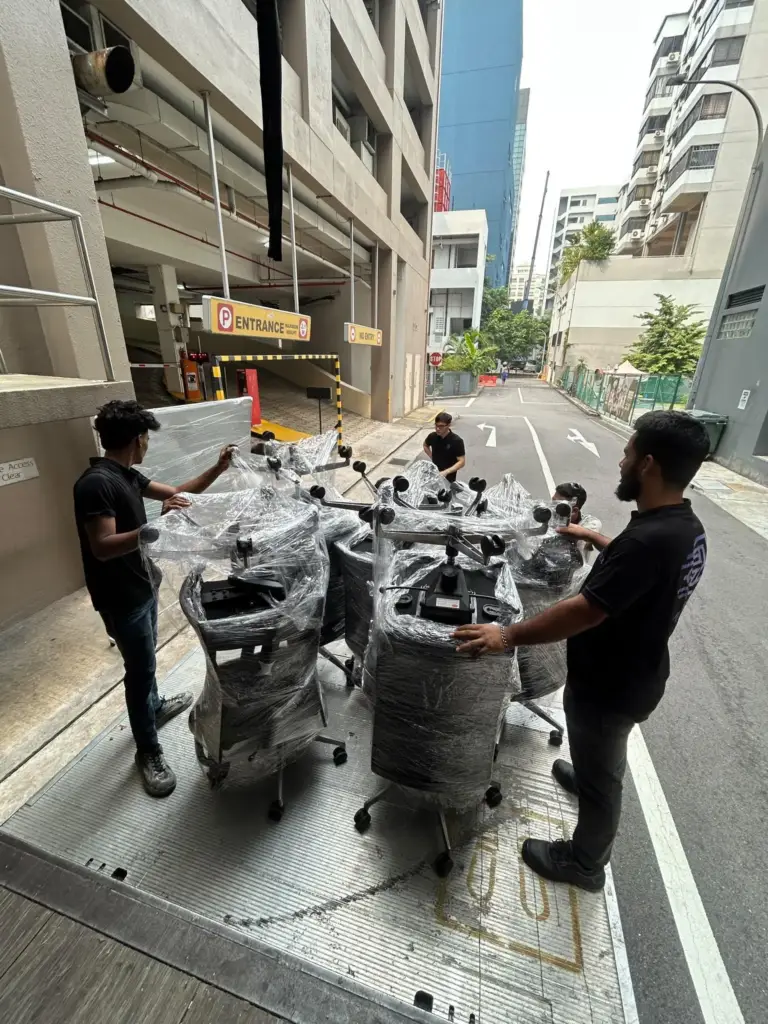 Office chairs shrink-wrapped by Mofex movers at a building loading bay