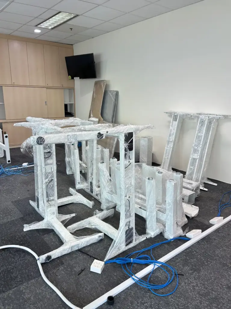 Dismantled desk frames wrapped and stacked during an office relocation