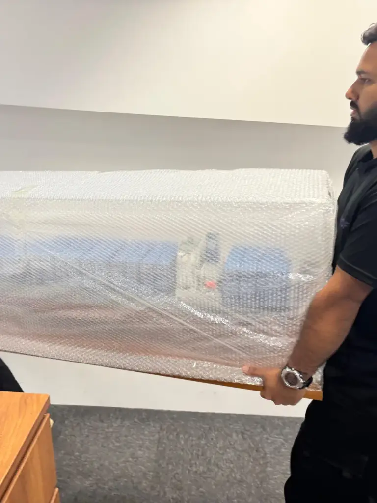 Mofex mover carrying a bubble-wrapped cabinet through an office