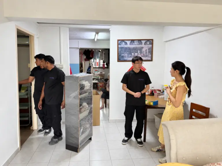 Mofex movers in uniform with a stretch-wrapped shelf, talking with a customer during an HDB flat move in Singapore