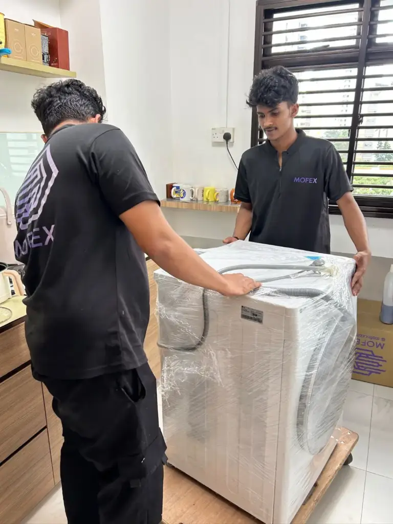 Mofex movers moving a shrink-wrapped washing machine on a dolly
