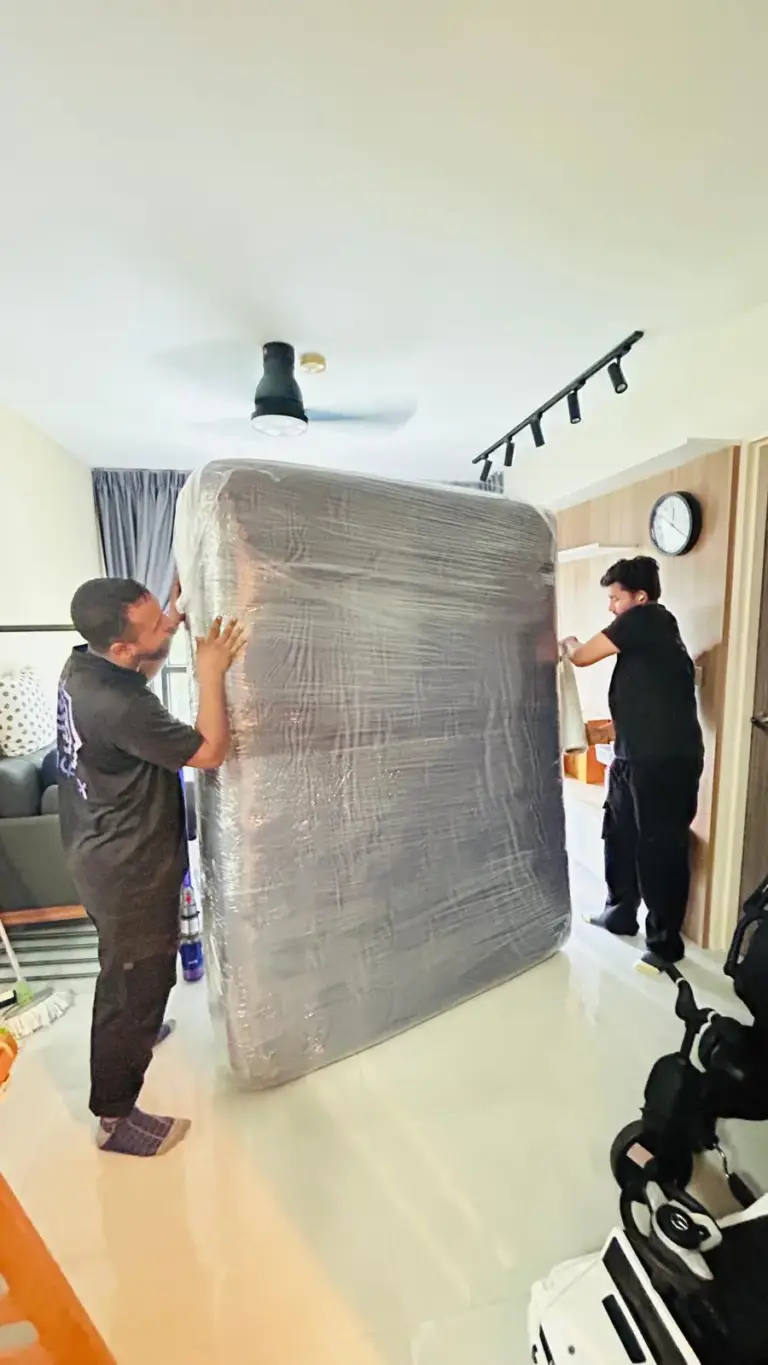 Two Mofex movers stretch-wrapping a mattress in a home before moving it
